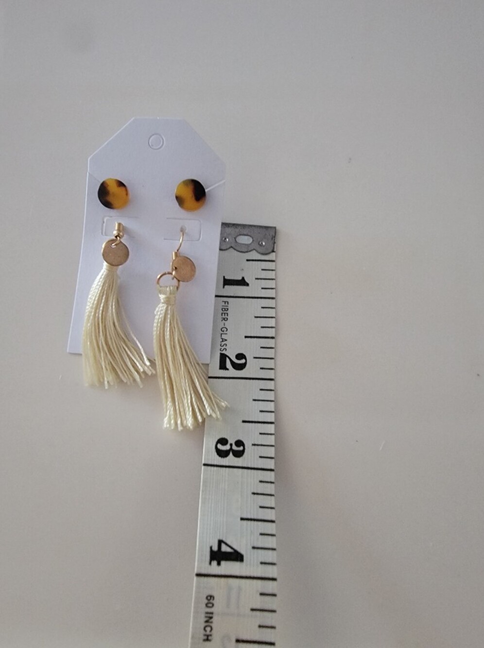 These are tortoise shell stud earrings with ivory silk tassels and gold-colored